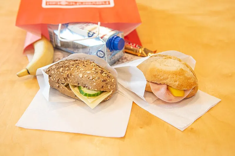 Lunchpaket mit belegten Brötchen, Obst und Getränk