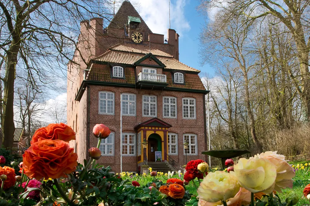 Schloss Ritzebüttel, ein Backsteinbau mit Turm, umgeben von Blumen